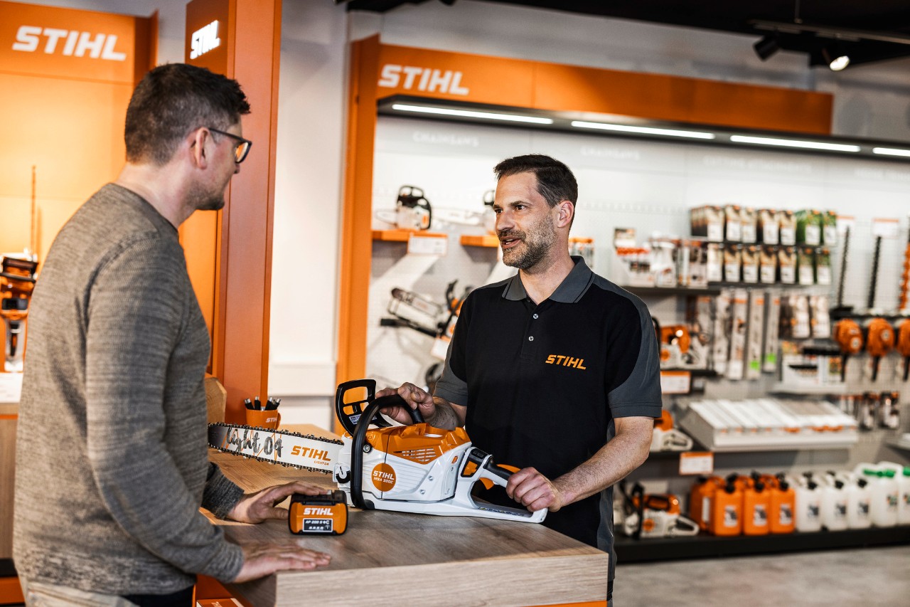 El concesionario STIHL asesora a los clientes sobre la motosierra inalámbrica STIHL MSA 300 en su sala de exposición