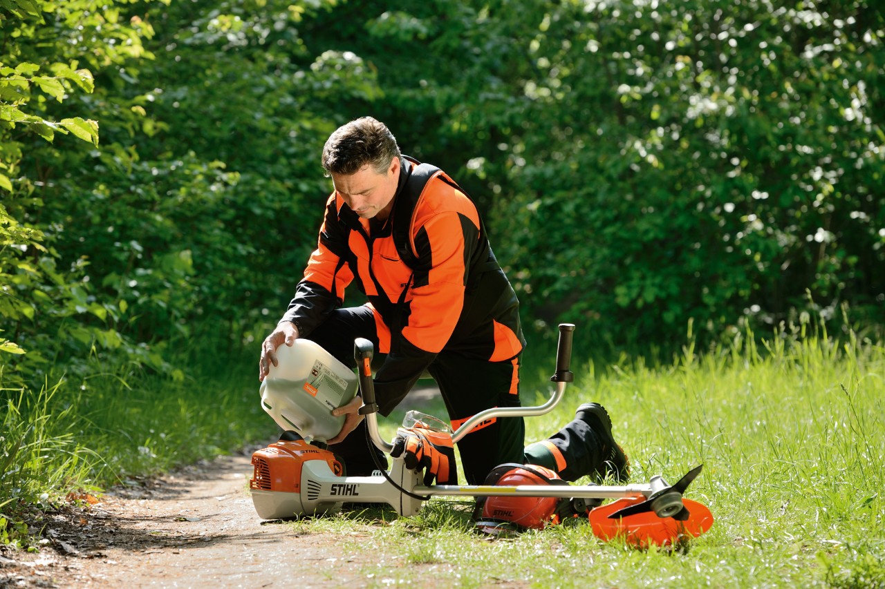 Un hombre llena la desbrozadora STIHL con una mezcla de gasolina y aceite