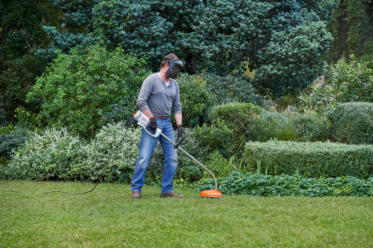 Un hombre con una desbrozadora eléctrica STIHL FSE 60 está de pie en una posición segura
