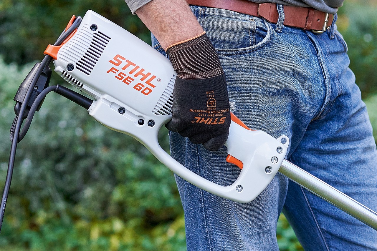 Un hombre acciona el interruptor para apagar la desbrozadora eléctrica STIHL FSE 60.