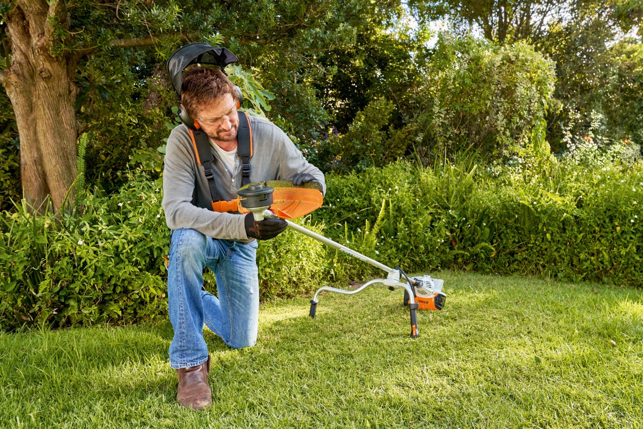 Un hombre prepara la desbrozadora en un jardín para cambiar el equipo de corte