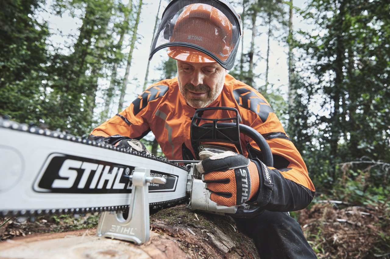 Un hombre con equipamiento de protección trabaja con una motosierra STIHL en el bosque